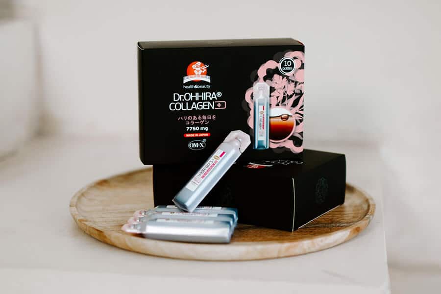 Dr.OHHIRA® KOLLAGEENI+ -pakkaus ja 20 ml:n juoma-ampullit puisella tarjottimella.